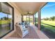 Relaxing screened lanai featuring comfortable seating, a ceiling fan, and a view of the lush green golf course at 6914 Grand Estuary Trl # 101, Bradenton, FL 34212