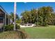Outdoor patio seating area surrounded by lush landscaping and a flagpole on a well-manicured lawn at 7218 Teal Creek Gln, Lakewood Ranch, FL 34202