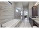Modern bathroom featuring a soaking tub, frameless shower, granite counters and dual vanities at 7218 Teal Creek Gln, Lakewood Ranch, FL 34202