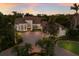 Stunning aerial view of a grand estate with a circular driveway, tile roof, and meticulously landscaped grounds at sunset at 7218 Teal Creek Gln, Lakewood Ranch, FL 34202