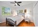 Well-lit bedroom has hardwood floors, window, ceiling fan, artwork, and a comfortable bed at 7231 Brambury Ct, Sarasota, FL 34238