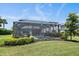 Landscaped backyard with lawn, bushes, and a screened-in pool area with patio at 7743 Nightfall Ter, Sarasota, FL 34241