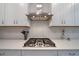 Close-up of gas cooktop and modern range hood in the kitchen, complemented by white subway tile backsplash at 7743 Nightfall Ter, Sarasota, FL 34241