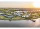 Beautiful aerial view of a community with a clubhouse, pool, lake, and tennis courts at sunset at 8195 Redonda Loop, Lakewood Ranch, FL 34202