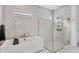 Bright white bathroom featuring walk-in shower with glass door, luxurious tub, and marble tile design at 8195 Redonda Loop, Lakewood Ranch, FL 34202