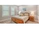 Comfortable bedroom with natural light, a wooden bed frame and matching nightstands on wood floors at 8713 Mangilli Rd, Sarasota, FL 34238