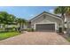 Well-maintained home featuring a gray facade, brick driveway, and lush landscaping with palm trees and green grass at 8713 Mangilli Rd, Sarasota, FL 34238
