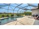 Screened-in pool with water feature and a stone fire pit with seating with lush green landscaping at 8713 Mangilli Rd, Sarasota, FL 34238