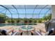 Resort-style screened-in pool area with fire pit, lounge chairs and lush landscaping at 8713 Mangilli Rd, Sarasota, FL 34238