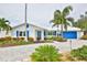 Charming white home with blue accents, a paved driveway, and lush tropical landscaping creating a welcoming curb appeal at 10108 Kingfisher E Rd, Bradenton, FL 34209