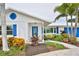 Close-up of a white home's entrance showcasing blue door and shutter accents, complemented by lush tropical landscaping at 10108 Kingfisher E Rd, Bradenton, FL 34209