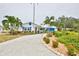Inviting white home features vibrant blue shutters and garage door, complemented by lush tropical landscaping and a patterned driveway at 10108 Kingfisher E Rd, Bradenton, FL 34209