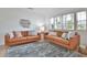 Bright living room showcasing two leather sofas, stylish rug, plantation shutters, and decorative fish art at 10108 Kingfisher E Rd, Bradenton, FL 34209