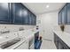 Laundry room with navy blue cabinets, a washer and dryer, and a sink at 10819 Wicker Park Pl, Palmetto, FL 34221