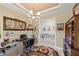 Well-lit office features a chandelier, neutral walls, and a view into the home's hallway at 10819 Wicker Park Pl, Palmetto, FL 34221