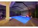 Screened in pool with blue lighting, surrounded by pavers, and plants for an attractive night swim at 10819 Wicker Park Pl, Palmetto, FL 34221