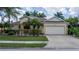 Well-maintained single-story home with a two-car garage, brick paved driveway, and lush tropical landscaping at 11592 57Th Street E Cir, Parrish, FL 34219