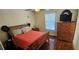 Cozy bedroom featuring hardwood floors, a wooden bed frame, and a matching dresser with a TV at 1218 Carmella Ln, Sarasota, FL 34243
