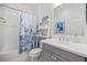 Bright bathroom featuring a tub with shower, gray vanity and coastal themed decor at 12706 Cobalt Ter, Bradenton, FL 34211