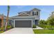 Charming two-story home featuring a modern gray facade, attached two-car garage, and well-maintained landscaping at 15001 Shady Palms Ln, Nokomis, FL 34275