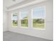 Bare room with neutral carpet and three windows overlooking a scenic outdoor view at 15001 Shady Palms Ln, Nokomis, FL 34275
