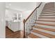 View of kitchen and staircase with wood steps and decorative wrought iron railing at 15001 Shady Palms Ln, Nokomis, FL 34275