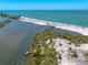 An aerial view of a sandy beach with a waterway and a wooden pier in the background at 1680 Lemon Bay Dr, Venice, FL 34293