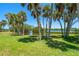 Beautiful backyard featuring lush green grass, mature palm trees, and serene water views at 1680 Lemon Bay Dr, Venice, FL 34293