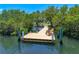 Aerial view of a dock surrounded by lush greenery, with a chair for relaxing by the water at 1680 Lemon Bay Dr, Venice, FL 34293