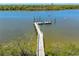 Scenic view of a wooden dock extending into calm waters, framed by lush green foliage at 1680 Lemon Bay Dr, Venice, FL 34293