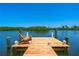 A wooden dock with an Adirondack chair overlooks a calm, picturesque body of water and lush mangroves at 1680 Lemon Bay Dr, Venice, FL 34293