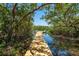 Scenic view of a wooden dock surrounded by lush greenery, leading to tranquil waters at 1680 Lemon Bay Dr, Venice, FL 34293