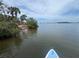 Peaceful view of a paddle board on the water with shoreline, palm trees, and clear skies in the distance at 1680 Lemon Bay Dr, Venice, FL 34293