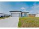 Bright single-story home with a two-car garage, modern front door, and manicured lawn under a clear sky at 18182 Steele Ave, Port Charlotte, FL 33948