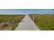 Wooden boardwalk leading to a beautiful beach with vegetation, sand, and turquoise ocean waters at 2301 Cass St, Sarasota, FL 34231