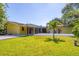 Exterior view of the backyard showing a house with yellow paint, the pool, patio, and surrounding greenery at 2410 Tanglewood Dr, Sarasota, FL 34239