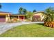 Inviting yellow home with a red front door, desert landscaping and circular driveway at 2410 Tanglewood Dr, Sarasota, FL 34239