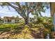 View of a backyard, with a large tree providing shade over the green grass and landscaping at 2531 Riverbluff Pkwy # V181, Sarasota, FL 34231