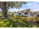Backyard view featuring well-maintained lawn, mature tree, landscaping, and the rear of the home at 2531 Riverbluff Pkwy # V181, Sarasota, FL 34231