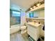 Well-lit bathroom featuring a tub with gray tiled walls, vanity and large mirror at 3325 Honeymoon Ln, Holiday, FL 34691
