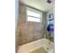 Bathroom with tub, tiled walls, shower head, and window for natural light at 3325 Honeymoon Ln, Holiday, FL 34691