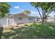 Back exterior view of the house with mature trees and a white vinyl fence at 3370 Harbor Lake Dr, Largo, FL 33770