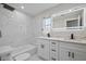 A bathroom with white marble-look tile, dual vanity and an LED mirror at 3370 Harbor Lake Dr, Largo, FL 33770