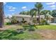 Charming home featuring well-manicured lawn and tropical landscaping with mature palm trees at 3370 Harbor Lake Dr, Largo, FL 33770