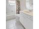 Bright bathroom featuring a shower/tub, neutral tiles, a floral shower curtain and sink with white cabinets at 4730 Old Farm Rd, Sarasota, FL 34233