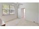 Bright bedroom with neutral carpet and paint, ceiling fan, large window and an open doorway to the bathroom at 4730 Old Farm Rd, Sarasota, FL 34233
