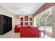Bright living room with plush red couches, custom built-ins, and sliding doors to the pool at 4730 Old Farm Rd, Sarasota, FL 34233