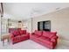 Open-concept living area featuring bright red sofas, adjacent kitchen, and neutral carpet for comfortable entertaining at 4730 Old Farm Rd, Sarasota, FL 34233