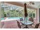 Covered patio with brick pavers and a table set, overlooking the screened pool area at 4730 Old Farm Rd, Sarasota, FL 34233