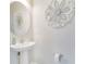 Charming powder room featuring a pedestal sink, decorative mirror and ornate flower wall art at 5514 Spanish Moss Cv, Bradenton, FL 34203